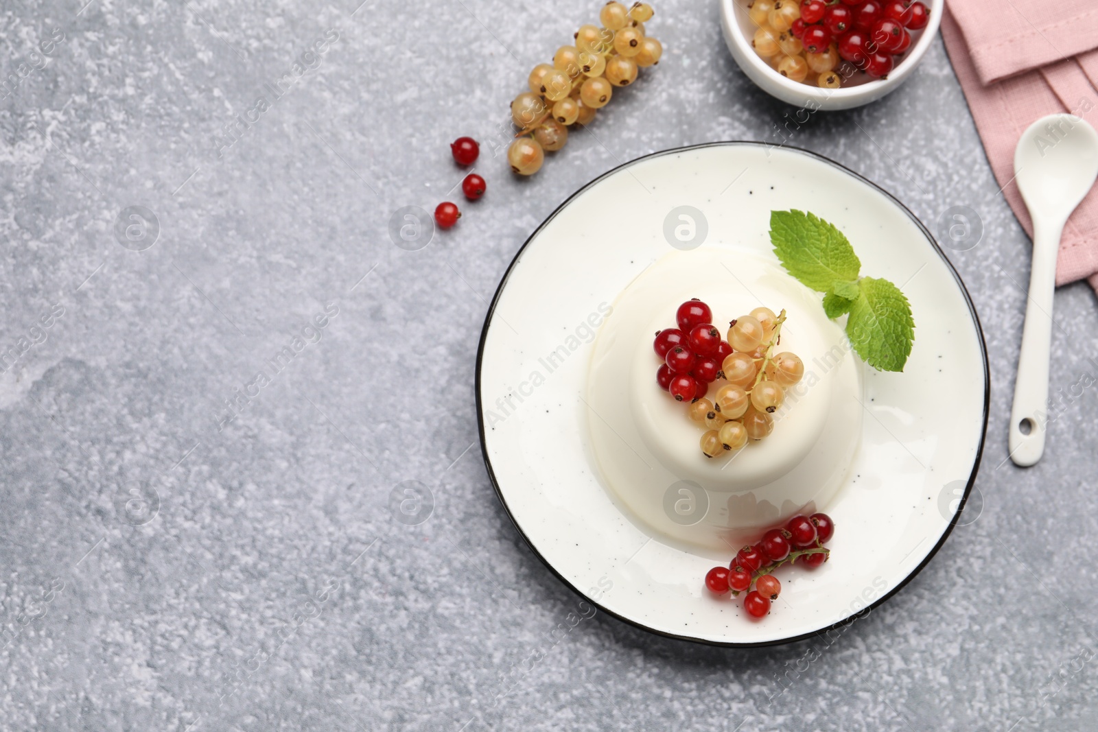 Tasty panna cotta with currants and mint on light grey table, flat lay. Space for text Photo of Tasty panna cotta with currants and mint on light grey table, flat lay. Space for text