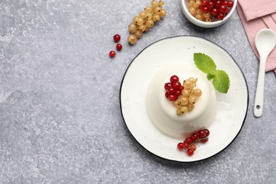 Photo of Tasty panna cotta with currants and mint on light grey table, flat lay. Space for text