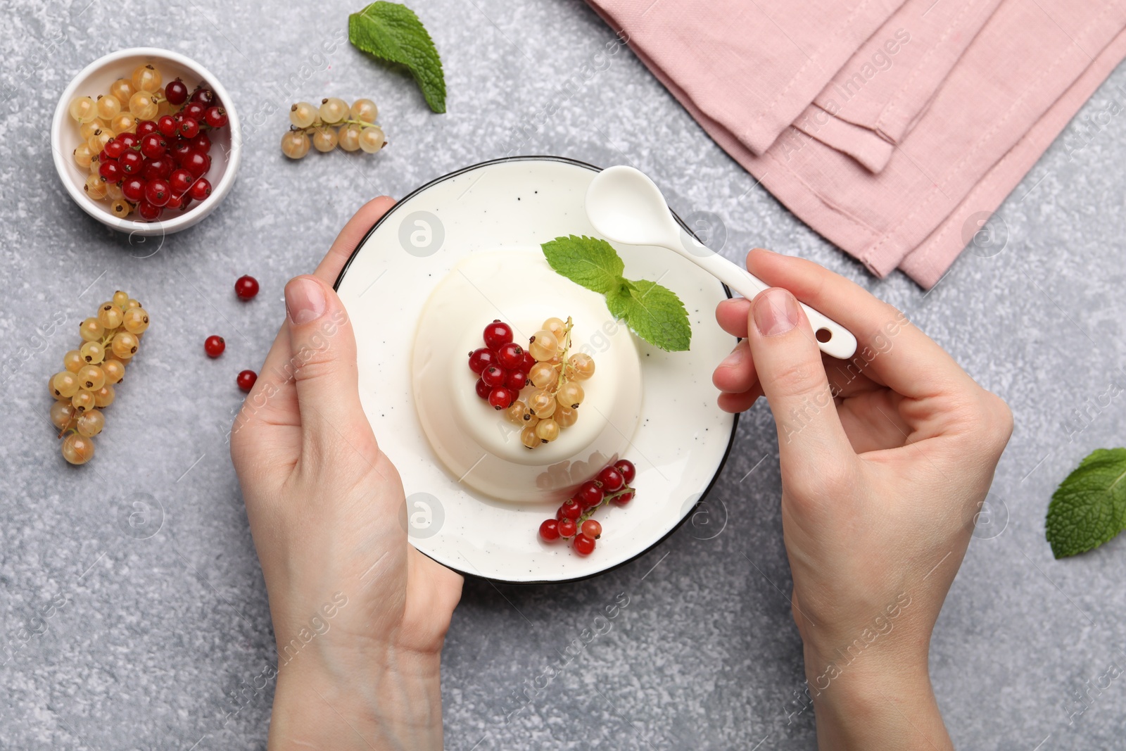 Woman eating tasty panna cotta with currants and mint at light grey table, top view Photo of Woman eating tasty panna cotta with currants and mint at light grey table, top view