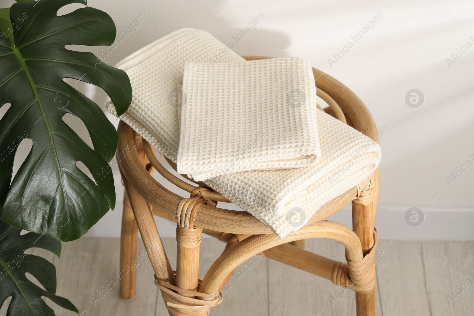 Photo of Folded waffle towels on wicker chair near light wall