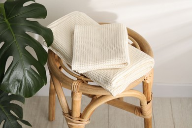 Photo of Folded waffle towels on wicker chair near light wall