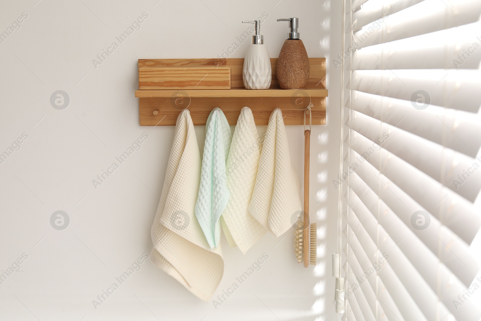 Photo of Clean waffle towels and brush hanging on hook rack in bathroom