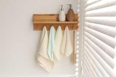 Photo of Clean waffle towels and brush hanging on hook rack in bathroom