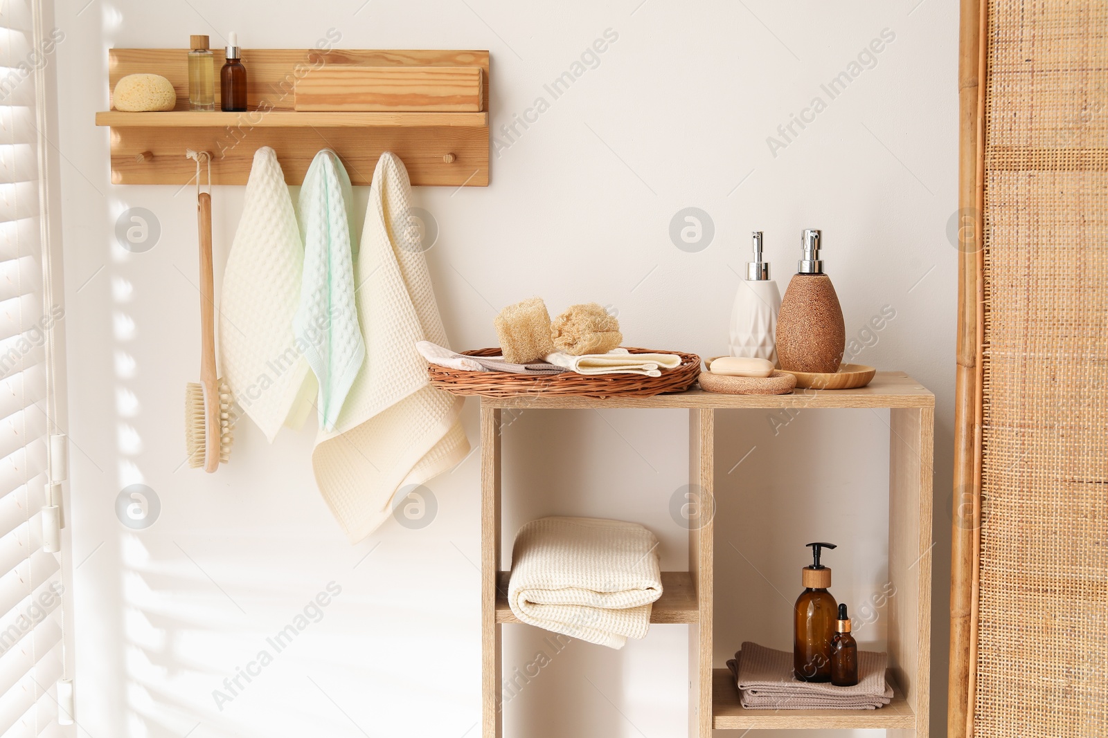 Photo of Clean waffle towels hanging on hook rack, brush and spa products in bathroom