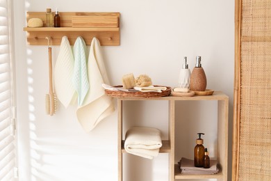 Photo of Clean waffle towels hanging on hook rack, brush and spa products in bathroom