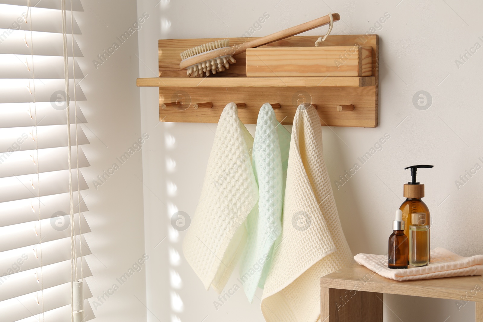 Photo of Clean waffle towels hanging on hook rack, brush and spa products in bathroom