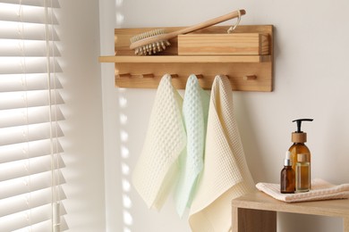 Photo of Clean waffle towels hanging on hook rack, brush and spa products in bathroom