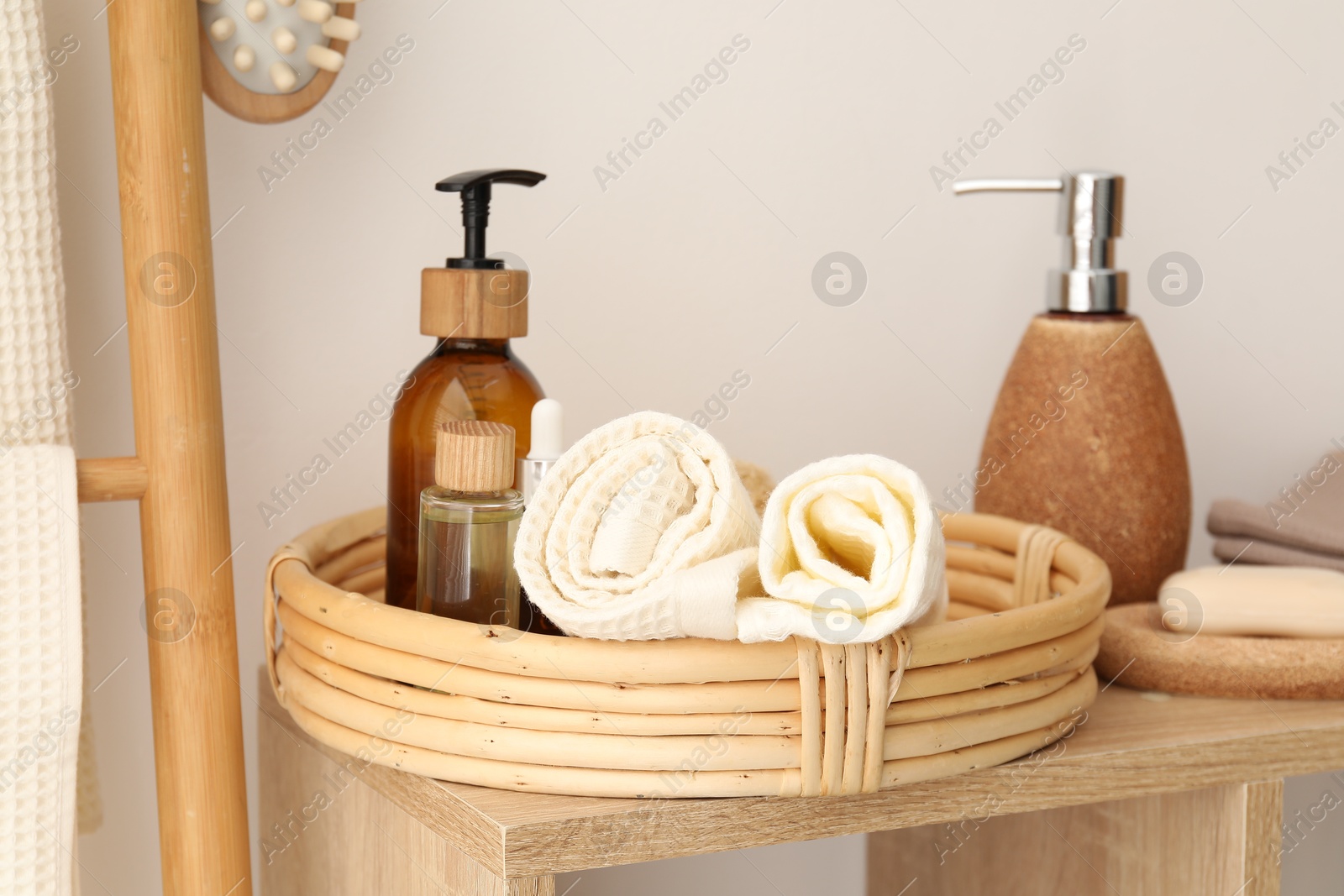 Photo of Clean waffle towels and spa products on shelf near white wall