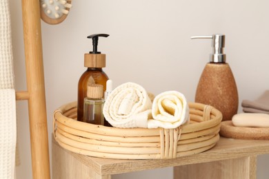 Photo of Clean waffle towels and spa products on shelf near white wall
