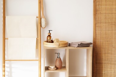 Photo of Clean waffle towels and spa products on shelving unit near white wall in bathroom
