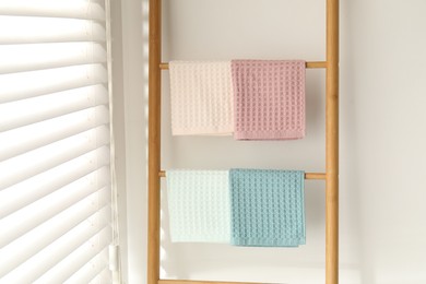 Photo of Clean waffle towels hanging on shelving unit near white wall