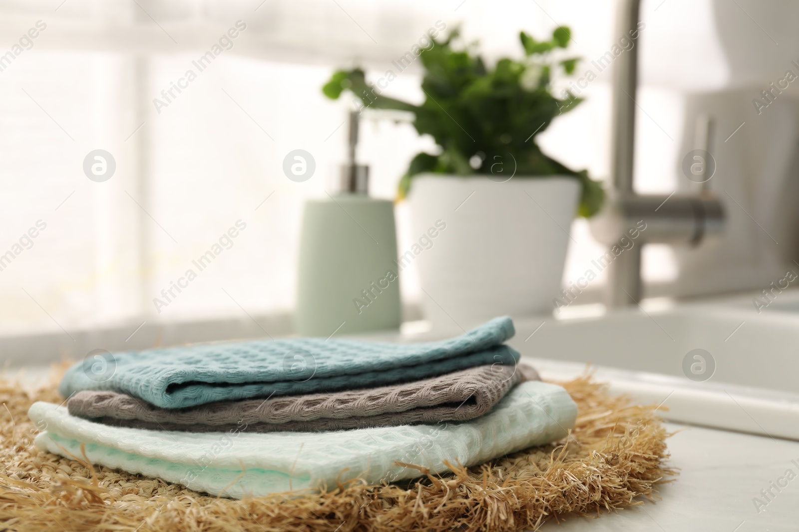 Photo of Clean waffle towels and wicker mat on white counter, closeup
