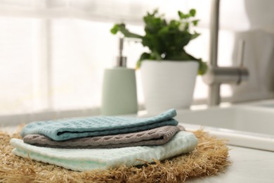 Photo of Clean waffle towels and wicker mat on white counter, closeup