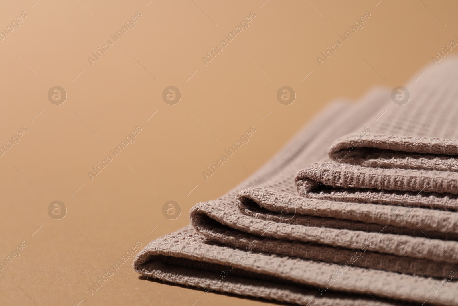 Photo of Folded waffle towels on light brown background, closeup. Space for text