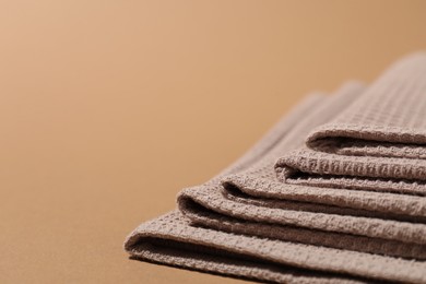 Photo of Folded waffle towels on light brown background, closeup. Space for text