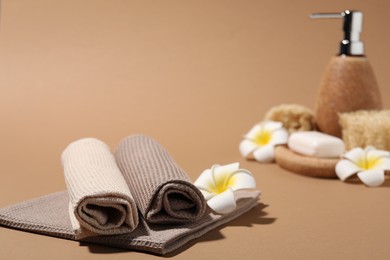 Photo of Clean waffle towels and plumeria flower on light brown background, closeup