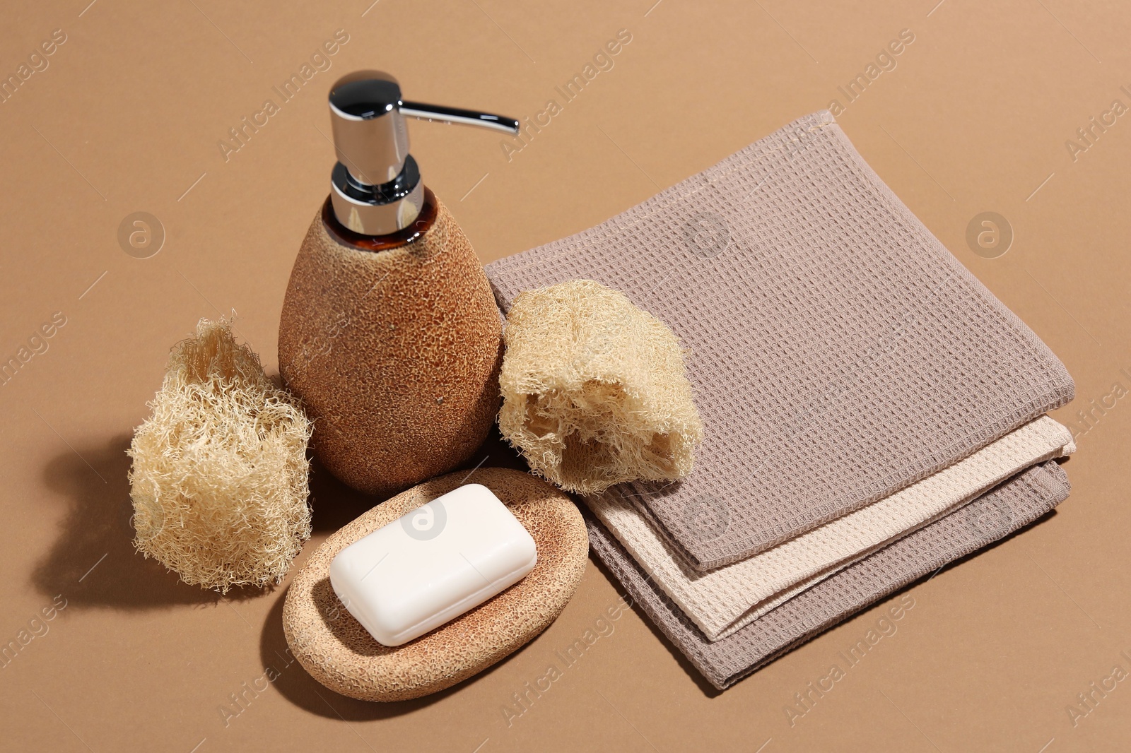 Photo of Folded waffle towels and spa products on light brown background, closeup