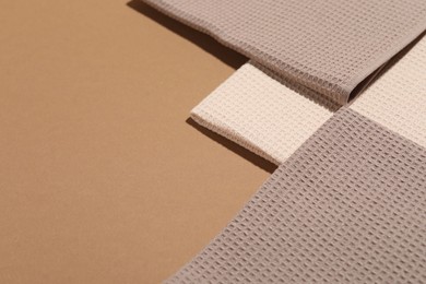 Photo of Folded waffle towels on light brown background, closeup. Space for text