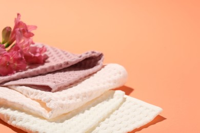 Photo of Folded waffle towels and flowers on coral background, closeup. Space for text