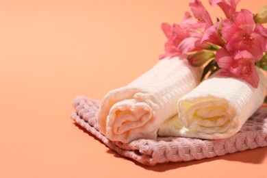 Photo of Clean waffle towels and flowers on coral background, closeup. Space for text