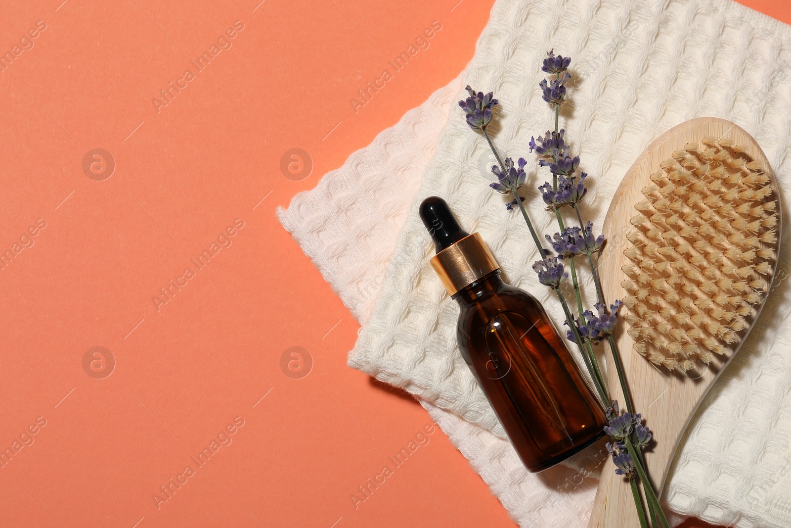 Photo of Clean waffle towels, lavender plant, dropper and brush on coral background, flat lay. Space for text