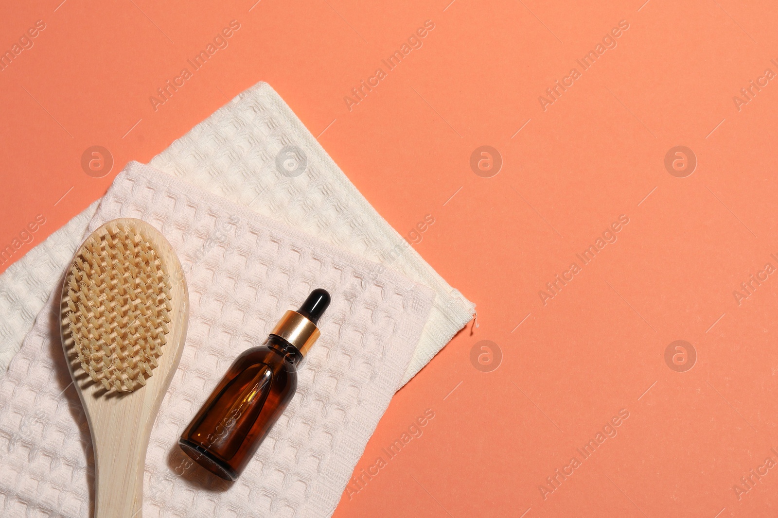 Photo of Clean waffle towels, dropper and brush on coral background, flat lay. Space for text