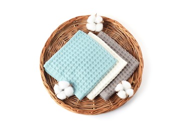 Photo of Clean waffle towels and cotton flowers on wicker surface isolated on white, top view