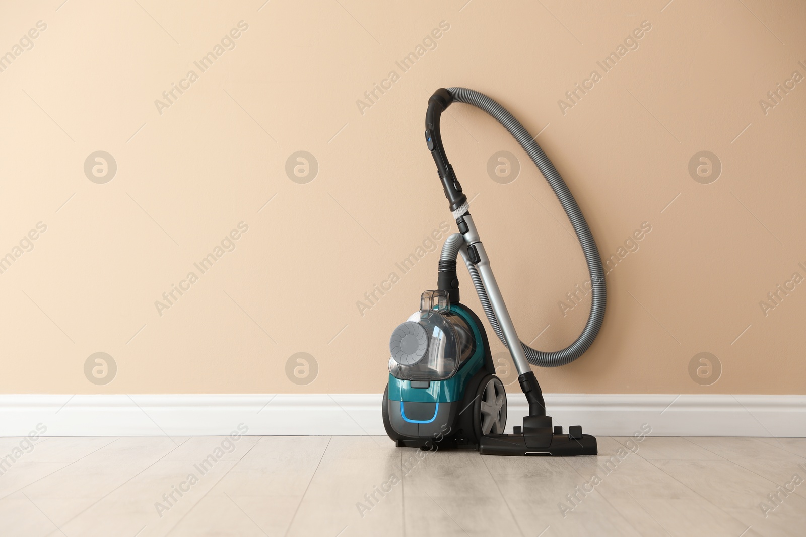One vacuum cleaner on floor near beige wall Photo of One vacuum cleaner on floor near beige wall
