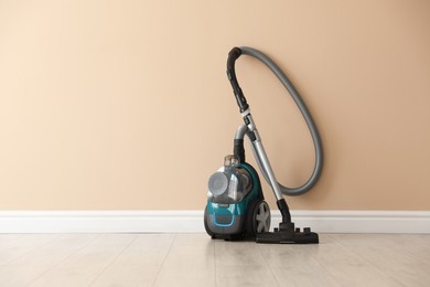 Photo of One vacuum cleaner on floor near beige wall