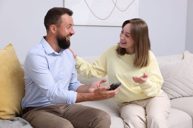Photo of Friends with smartphone laughing on sofa at home
