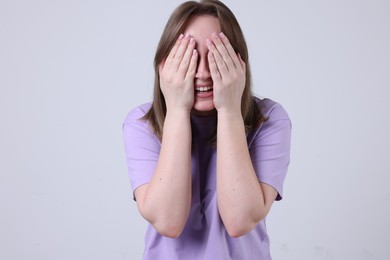 Photo of Woman covering eyes with hands and laughing on grey background