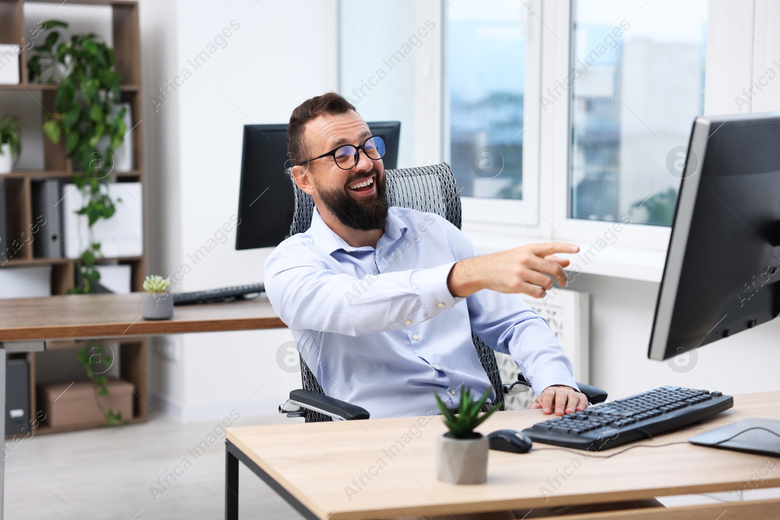 Photo of Man in glasses laughing at table in office