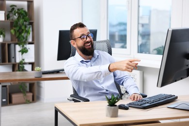 Photo of Man in glasses laughing at table in office