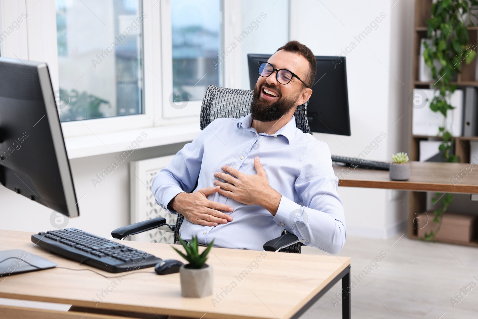 Photo of Man in glasses laughing at table in office