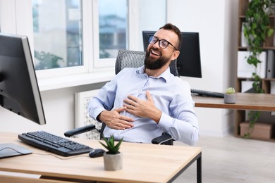 Photo of Man in glasses laughing at table in office