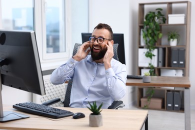 Photo of Man in glasses laughing at table in office