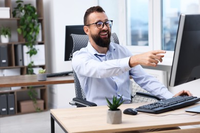 Photo of Man in glasses laughing at table in office