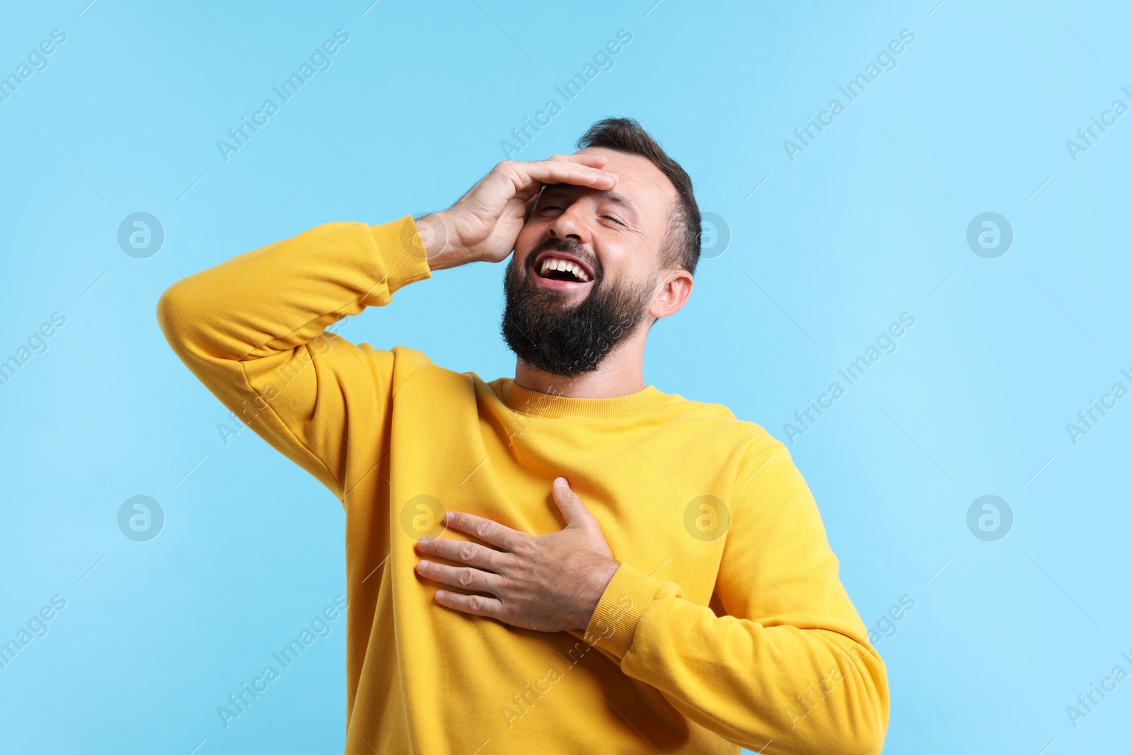 Photo of Handsome man laughing on light blue background