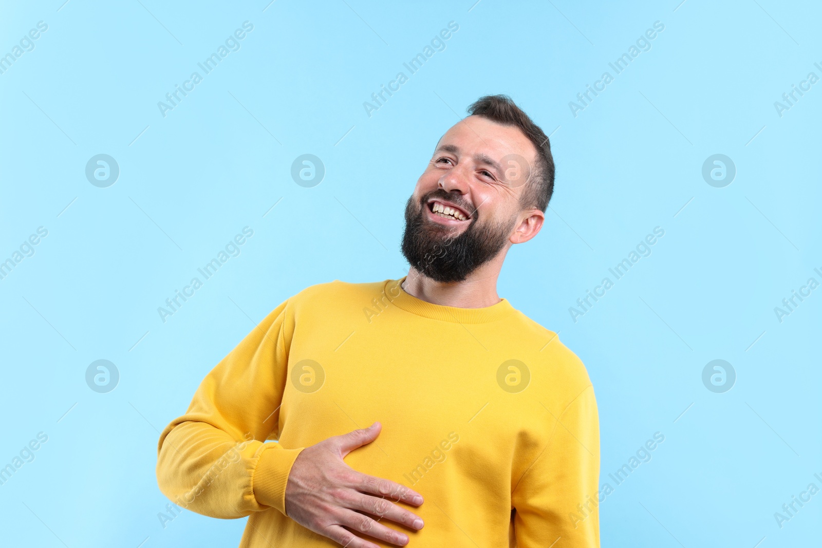 Photo of Handsome man laughing on light blue background