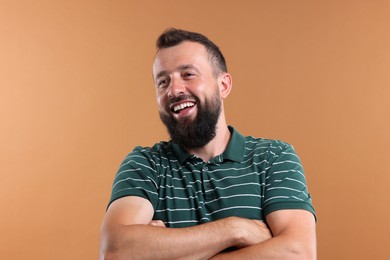 Photo of Handsome man with crossed arms laughing on brown background