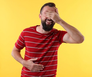 Photo of Man covering eyes and laughing on yellow background