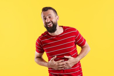 Photo of Handsome man laughing on yellow background. Positive emotion