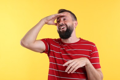 Photo of Handsome man laughing on yellow background. Positive emotion