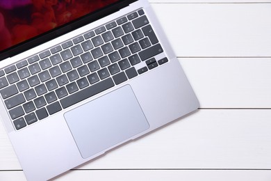 Photo of Laptop keyboard on white wooden table, top view. Space for text
