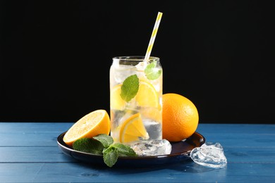 Photo of Sparkling water with orange, ice and mint in glass on blue wooden table, closeup
