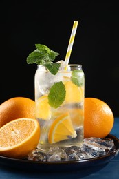 Photo of Sparkling water with orange, ice and mint in glass on blue wooden table, closeup