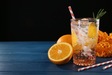 Photo of Sparkling water with orange in glass, fresh fruits and straws on blue wooden table, closeup. Space for text