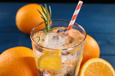 Photo of Refreshing soda water with ice and orange on blue table, closeup