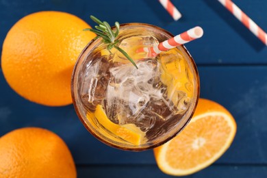 Photo of Refreshing soda water with ice and orange on blue wooden table, flat lay