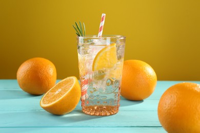 Photo of Refreshing soda water with ice and orange on light blue wooden table, closeup